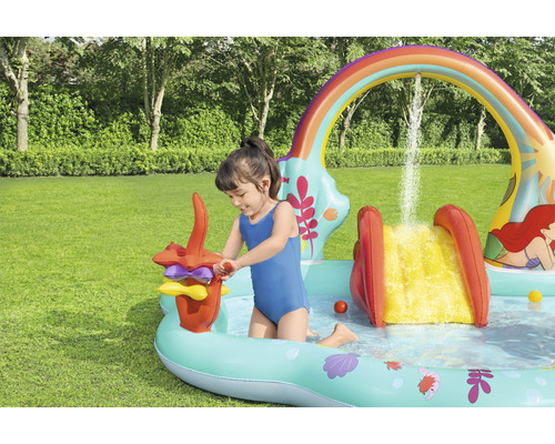 Dítě si hraje v nafukovacím brouzdališti se skluzavkou a vodními hrami na zahradě