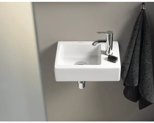 Malé umyvadlo s vodovodní baterií, kartáčem a ručníkem