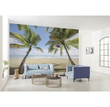 Obývací pokoj s fototapetou zobrazující tropickou scénu s palmami a pláží, s nábytkem, jako je pohovka a křesla.