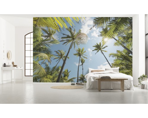 Světlá místnost s fototapetou s motivem palem, postelí a dekorací