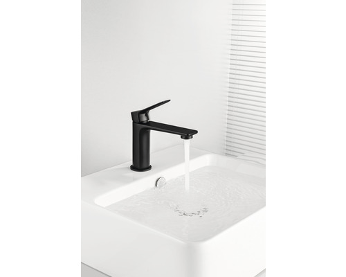 Černá umyvadlová baterie s tekoucí vodou v umyvadle.