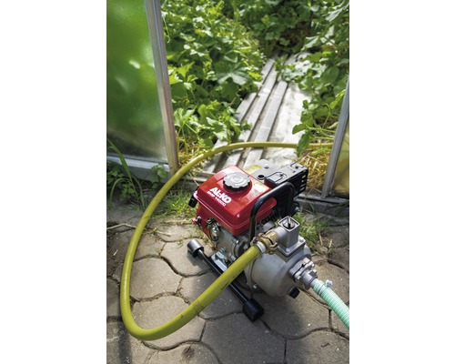 Motorové čerpadlo s hadicí na zahradě pro zavlažování