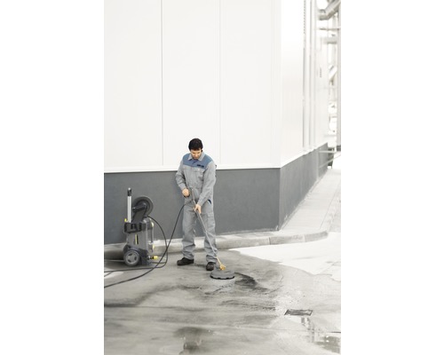 Muž čistí povrch pomocí vysokotlakého čističe a čističe povrchů