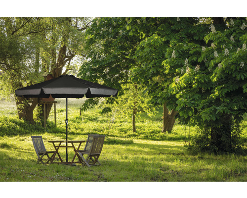 Zahradní scéna se stolem, židlemi a slunečníkem na zeleném trávníku