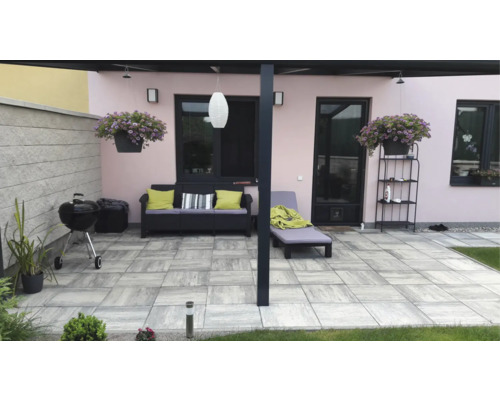 Upravená terasa se zahradním nábytkem, grilem a rostlinami pro venkovní použití.