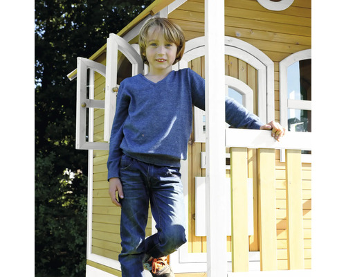 Chlapec před dřevěným herním domkem na zahradě