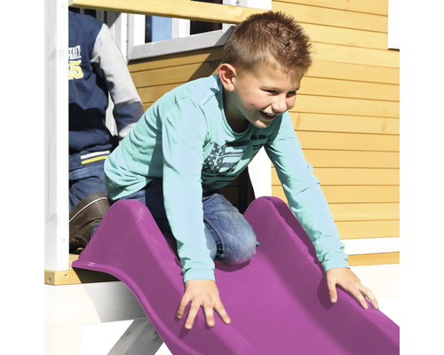 Chlapec klouže na plastové skluzavce na hřišti.