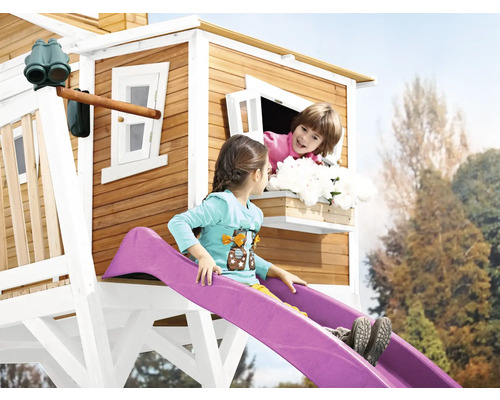 Dětský hrací domek se skluzavkou a dvě dívky hrající si na zahradě.