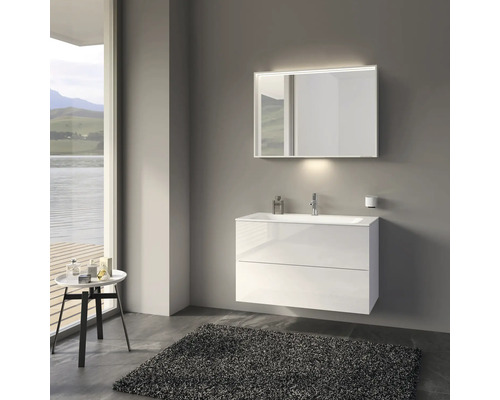 Moderní koupelna s bílou umyvadlovou skříňkou, zrcadlem s osvětlením a šedým kobercem.