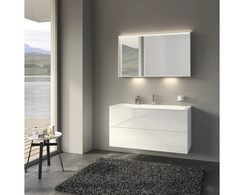 Koupelna s bílou skříňkou pod umyvadlo, osvětleným zrcadlem a kobercem