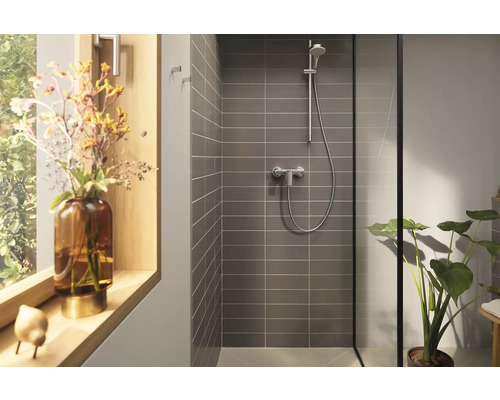 Moderní sprchový kout s šedými obklady, sprchovou armaturou a pokojovou rostlinou