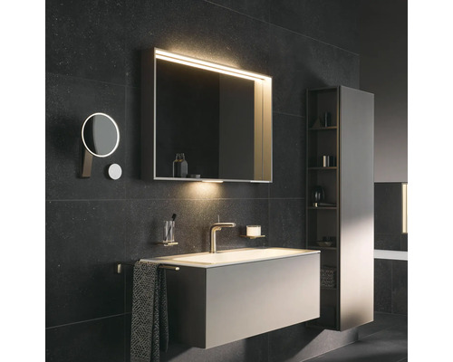 Moderní koupelna s umyvadlem, osvětlenou zrcadlovou skříňkou, kosmetickým zrcadlem a vysokou skříňkou pro úložný prostor