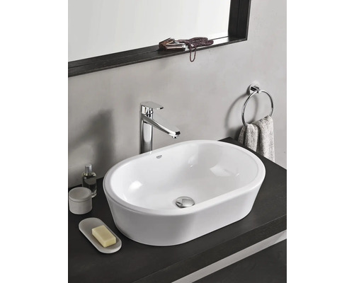 Moderní umyvadlo v koupelně s baterií, držákem na ručníky a doplňky na tmavém povrchu