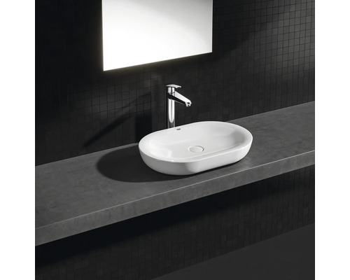 Keramické umyvadlo na desce s baterií na poličce v koupelně.