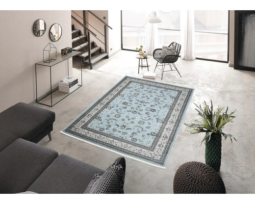 Obývací pokoj se světlým kobercem s květinovým vzorem, pohovkou a schodištěm