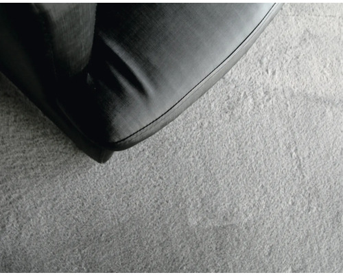 Detail šedého koberce vedle kusu nábytku