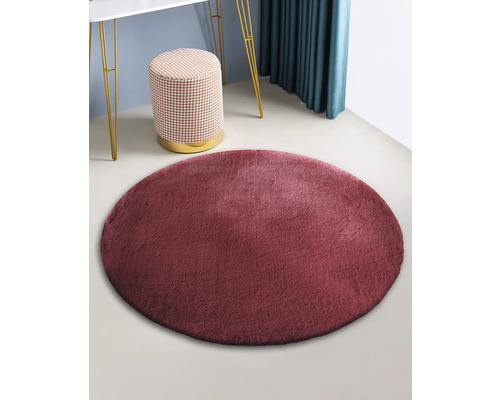 Kulatý koberec z umělé kožešiny v místnosti se stoličkou a stolem