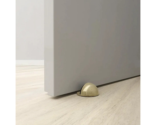 Zlatý kovový dveřní doraz namontovaný na dveřích