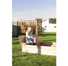 Dívka si hraje na zahradě v dřevěném pískovišti s posezením.