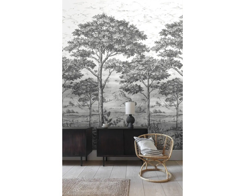 Pohled na místnost s tapetou se vzorem, komodou a ratanovým křeslem