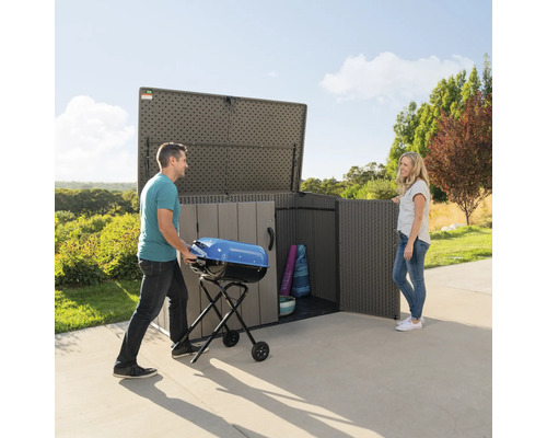 Prostorná zahradní skříň s mužem, který do ní vkládá gril, a ženou stojící vedle