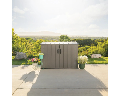 Plastová zahradní skříň s dvoukřídlými dveřmi a madly před krajinou.