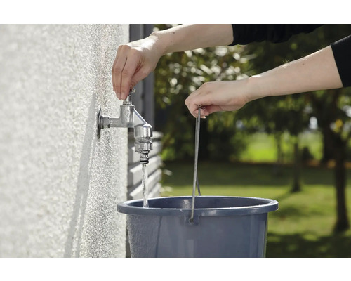 Osoba napouští vodu z kohoutku do kbelíku.