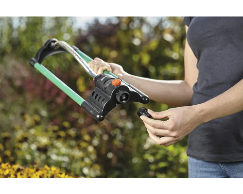 Žena montuje zahradní zavlažovač na zahradě