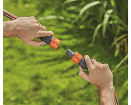 Dvě ruce spojují zahradní hadicovou spojku.