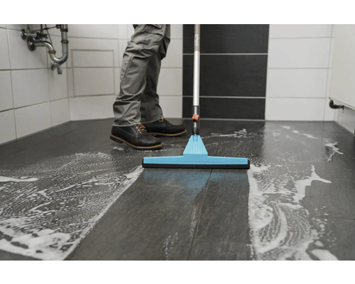 Čisticí prostředek vytírá podlahu v koupelně čisticím prostředkem a stěrkou