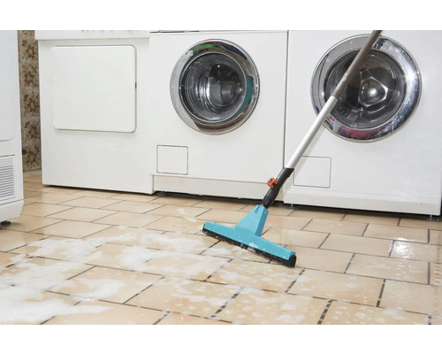 Mop se stěrkou před pračkami na dlážděné podlaze