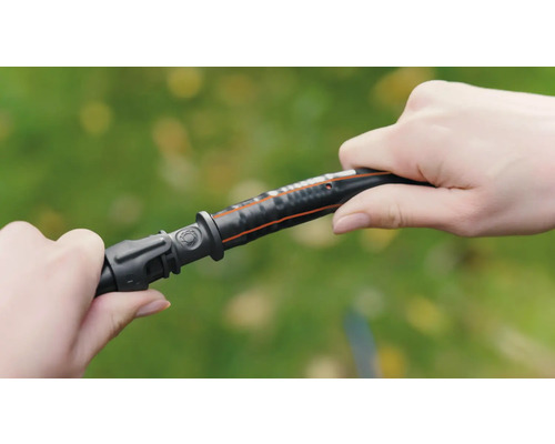 Osoba připojuje díl zahradní hadice k zahradní hadici.