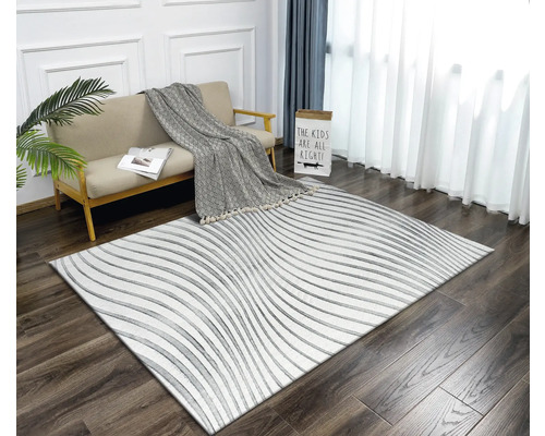Obývací pokoj s pohovkou, dekou a kobercem s lineárním vzorem na dřevěné podlaze