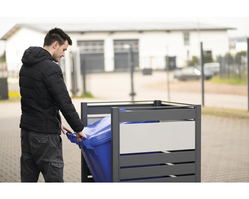 Muž zasouvá modrou popelnici do šedého boxu na popelnice