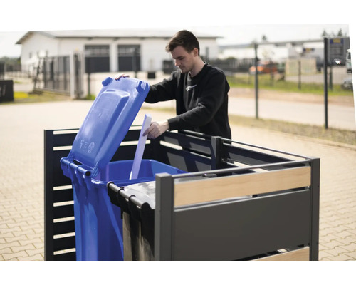 Muž otevírá modrou popelnici v boxu na popelnice