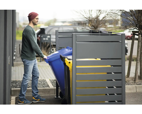 Muž zasouvá popelnici do boxu na popelnice
