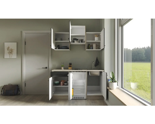 Kompaktní kuchyňská linka s dřezem, varnou deskou a lednicí ve světlé místnosti.