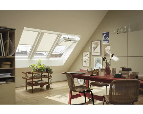 Světlý podkrovní pokoj s střešními okny, roletami, červeným stolem, židlemi a dekoracemi pro útulnou atmosféru.