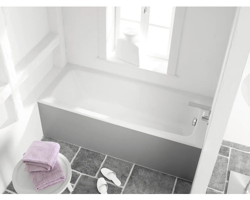 Koupelna s vanou, ručníky a pantoflemi na šedé dlažbě