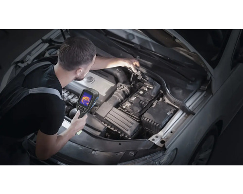 Muž kontroluje motorový prostor automobilu pomocí termokamery.