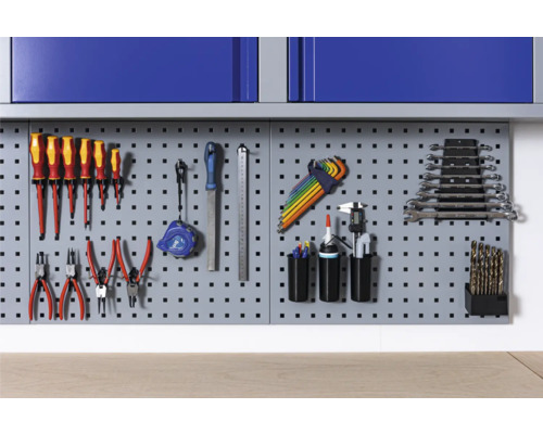 Děrovaná stěna na nářadí s různým nářadím, jako jsou šroubováky, kleště a klíče