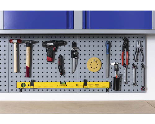 Děrovaná stěna na nářadí s kladivem, akumulátorovým šroubovákem, klíčem, pilníkem a vodováhou