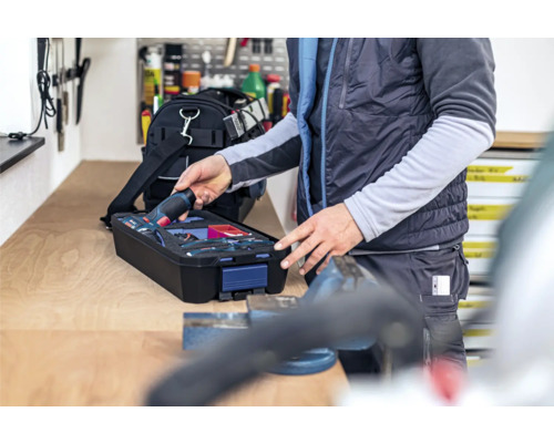 Osoba vyjímá akumulátorový šroubovák z kufříku s nářadím