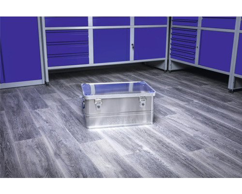 Hliníkový box na nářadí na podlaze dílny před modrými skříněmi na nářadí