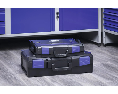 Dva černé kufříky na nářadí různých velikostí naskládané před modrou skříní na nářadí.