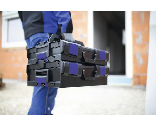 Osoba nese dva černé kufříky s nářadím.