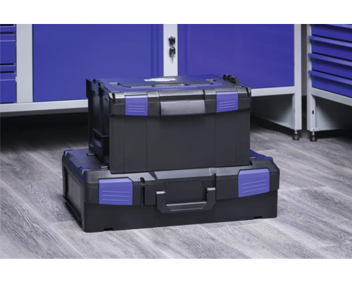 Dva černé kufříky na nářadí s modrými uzávěry naskládané před modrou dílenskou skříní.