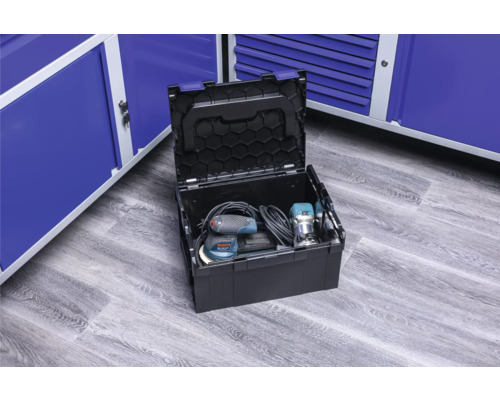 Otevřená bedna na nářadí s elektrickým nářadím před modrými kovovými skříněmi