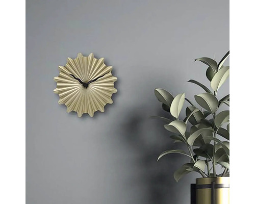 Dekorativní zlaté nástěnné hodiny s černou ručičkou vedle pokojové rostliny