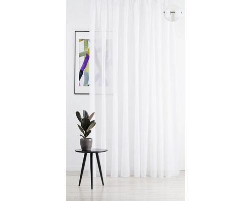 Bílý, průhledný závěs vedle příručního stolku a zarámovaného obrazu.